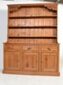 A good quality antique style country pine dresser raised on a plinth base with a series of short