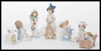 A group of Nao ( Lladro ) ceramic  figurines of children to include child sleeping in bed, child