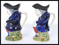 A pair of 19th century Victorian Staffordshire Toby Jugs raised on yellow and green majolica base