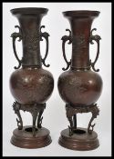 A pair of 19th century Japanese bronze vases of baluster form having twin scrolled handles with