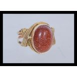 A 14ct gold ring having a large oval goldstone cab