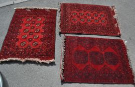 A collection of three 20th century rugs with red ground. The dimensions are 81cm x 116cm, 75cm x