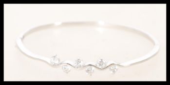 A silver bangle with cubic zirconia in prong setti