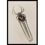 A 20th century silver bookmark with a spider finial having an inlaid red teardrop stone.