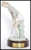 A Lladro ceramic figurine of a lady golfer with putter ( 4851 ) raised on a wooden base with applied