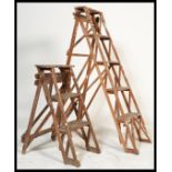 Two vintage 20th Century lattice Industrial framed wooden step ladders of differing sizes, the
