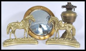 A collection of brass items to include brass horses, circular brass fish eye mirror and an oil lamp.
