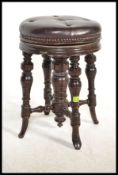 A Victorian mahogany revolving piano stool with splay turned supports with a leather button back