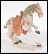A Chinese Tang dynasty style ceramic figurine of a horse raised on a plinth base with painted