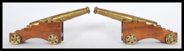A pair of early 20th century cast brass desk top cannons mounted on wooden bases with working