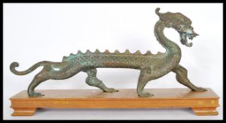 A 19th century Chinese bronze figurine of a dragon of elongated form having a scrolled tail being
