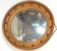 A Regency style gilt circular convex wall mirror, the frame finished in gilt with ball finial