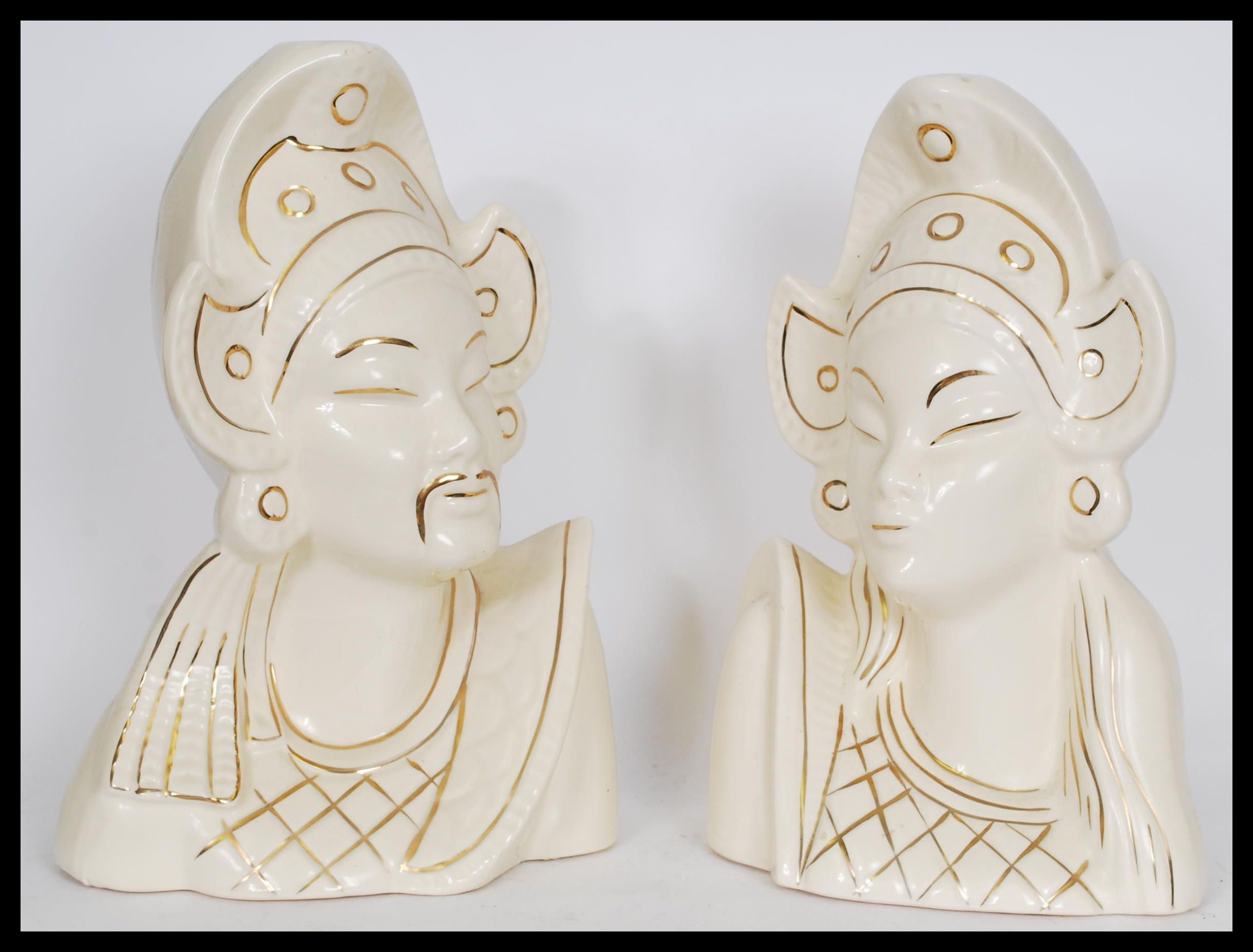 A pair of Asiatic white ceramic bust figures depicting a man and a woman in traditional dress with