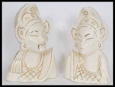 A pair of Asiatic white ceramic bust figures depicting a man and a woman in traditional dress with