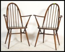 A pair of vintage Ercol Windsor hoop and spindle back carver dining chairs raised on tapered legs.