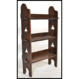 A Victorian Arts & Crafts oak open bookcase shelf having pierced sides with a series of central