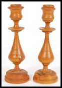 A 19th century pair of treen wooden candlesticks having turned knopped columns and sconces to the