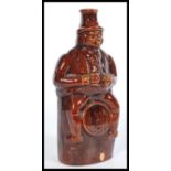 A 19th century salt glazed stoneware bottle flask depicting a Victorian man sitting on a barrel with