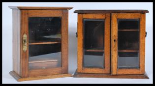 A glazed Edwardian oak smokers cabinet with inner drawer, together with another of similar form.