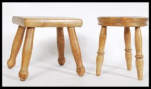 Two vintage pine milking stools, one with a square top and the other a circular top, both raised