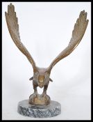 An early 20th century bronze figurine of an eagle lading with wings spread raised on a circular