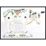 A 19th / 20th Century Delft ceramic figurine of a cow having hand painted floral sprays with painted