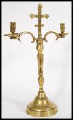 An 18th century ecclesiastical brass candelabra raised on a circular base with twin scroll arms