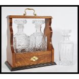 A vintage 20th century oak Tantalus with two glass decanters with geometric shaping, having a