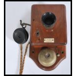 An early 20th century wall mounted telephone having an oak back and case with bakelite mouth and ear