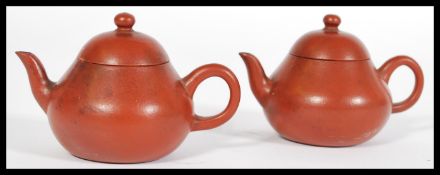 A pair of early 20th Century Chinese Yixing terracotta teapots of simple form, signed to the handles