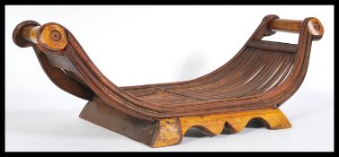 A vintage 20th century cane cheese sled having scrolled ends raised on shaped wooden supports.