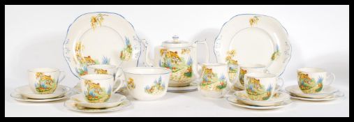 A vintage 20th Century Art Deco bone china tea service, brightly decorated with cottages and
