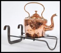 An early 20th century cast metal sliding fireplace trivet with a copper kettle of similar age.
