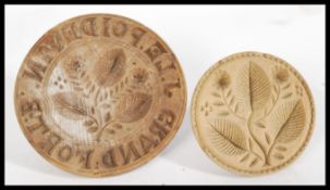 A pair of 19th century wooden butter moulds, having leaf and floral designs with one bearing the