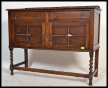 A 1920's oak sideboard with quarter panel cupboard doors and raised on spindle turned legs