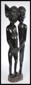 A west African polished wood fertility sculpture depicting two supernatural figures raised on a