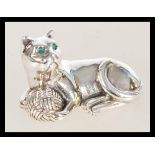 A vintage 20th century sterling silver figure of a cat with emerald eyes playing with a ball of