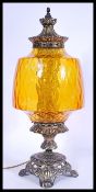 A vintage 20th century table lamp in the form of an antique oil lamp having an amber glass reservoir