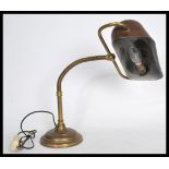 A vintage 20th century brass bankers desk lamp raised on a stepped circular base with adjustable