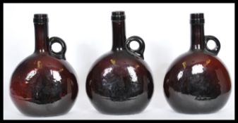 A set of three 19th century Dutch amber glass wine flask bottles having moon flask shaped bodies