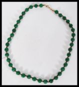 A Chinese green jade bead necklace having small gi