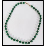 A Chinese green jade bead necklace having small gi