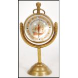 A contemporary brass Roman style fish eye ball clock raised on a brass base with nautical maritime