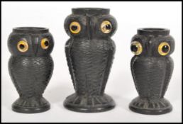 Three small wooden candle stick holders in the form of owls with carved detailing and yellow glass