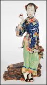 A Chinese ceramic figurine of a maiden seated having hand detailed floral motifs with character