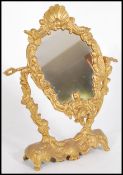 A 20th century Art Nouveau gilded metal ladies vanity swing mirror of rococo form being adorned with