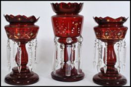 A 19th century Victorian garniture of cranberry glass lustres, to include two matching with with