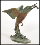 A cold cast bronze figurine of a Kingfisher in flight carrying a fish in its beak rising from water,