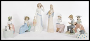 A collection of NAO / Lladro porcelain figurines to include a hooded figure of a woman with a jug, a