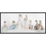 A collection of NAO / Lladro porcelain figurines to include a hooded figure of a woman with a jug, a